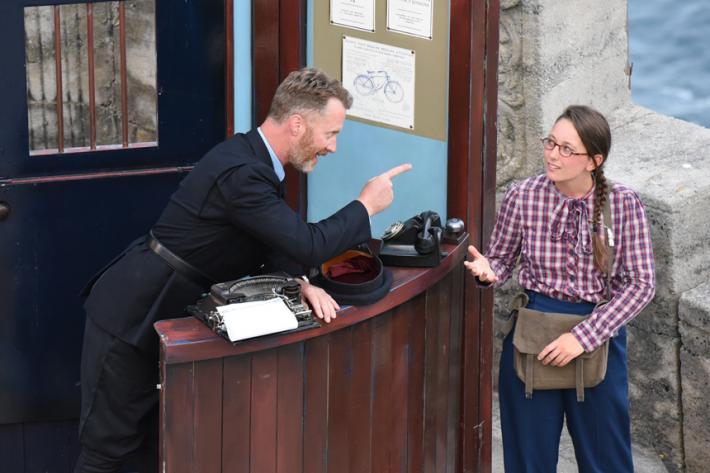 An actor dressed as a policeman gives advice to a young woman