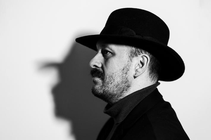 Black and white photo portrait of a man in profile wearing a black hat