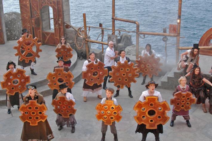 A group of actors in steam punk costumes carrying cogs and mechanical gadgets