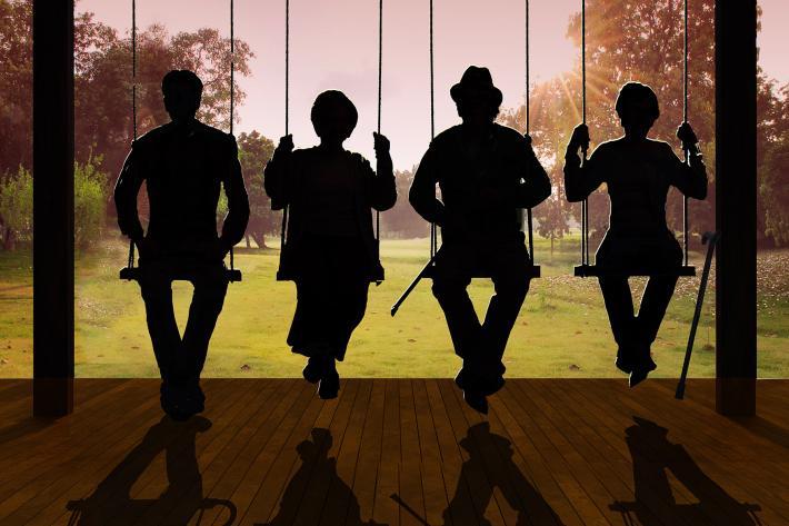 Silhouette of four people sitting on a community swing