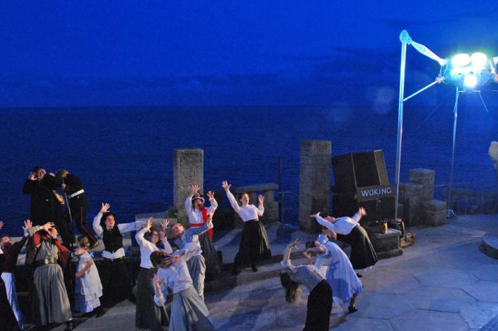 A crowd of actors in victorian costume recoil from a great metal monster from Mars