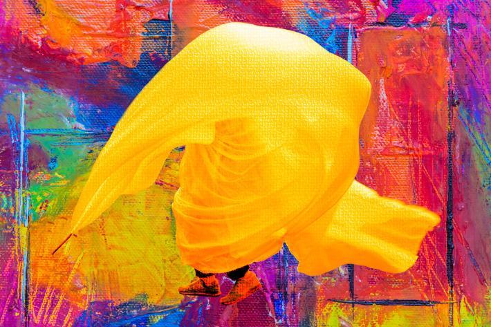 A colourful, shrouded figure dancing in an abstract background