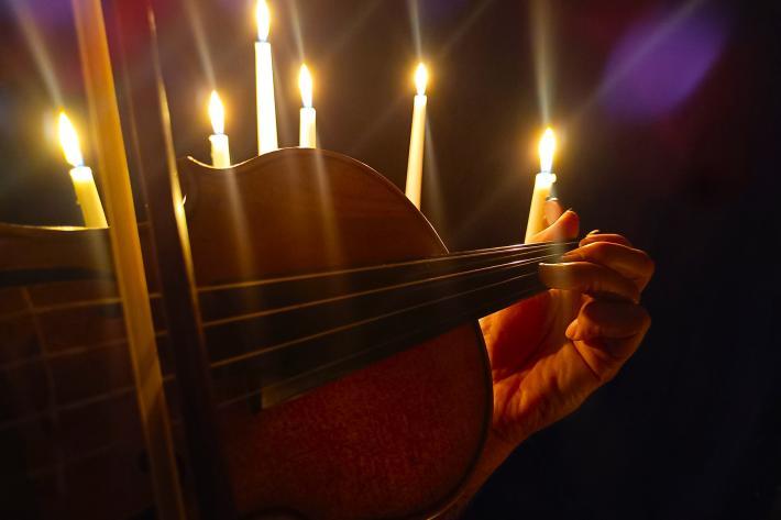 Hand playing a violin by candlelight