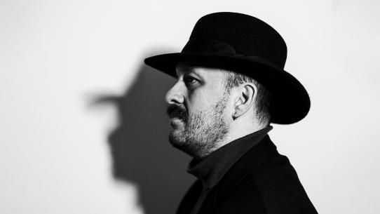 Black and white photo portrait of a man in profile wearing a black hat
